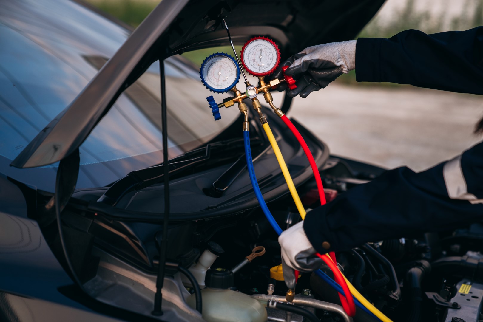 Mechanic performing a test on a car AC system